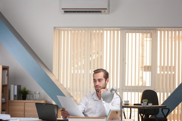 young-man-working-office-with-operating-air-conditioner_392895-238896